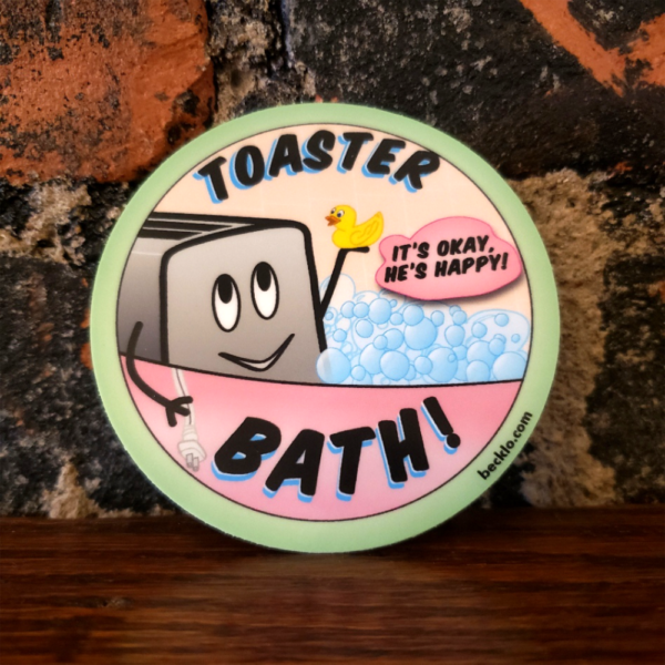 A 3" round sticker with a smiling gray toaster in a pink bathtub filled with bubbles. It has stick figure arms; the left arm is holding up a yellow rubber ducky. The right arm rests outside of the tub and holds his unplugged power cord. Text around the circle says, "TOASTER BATH!" in black text with a blue drop shadow. In a pink text bubble, black text says, "It's okay, he's happy!" A mint green border is on the edge, and "becklo.com" is written in black text.